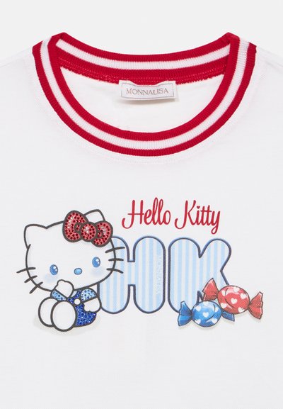 T-shirt blanc avec un col côtelé rayé rouge et blanc. Graphique de Hello Kitty avec un nœud, une tenue bleue et des accents de bonbons colorés.