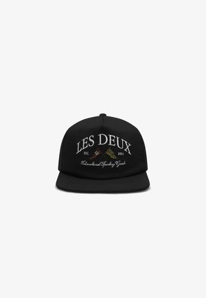 Black cap featuring embroidered text "LES DEUX" and "Est. 2011" in white, with decorative elements. Stiff brim and adjustable strap at the back.