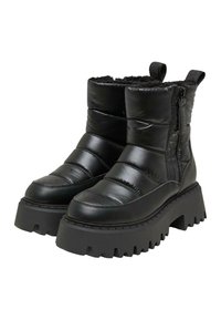 Bottines noires isolées à finition brillante, tige rembourrée, fermeture zippée latérale et semelle en caoutchouc épaisse avec rainures profondes pour une meilleure traction.
