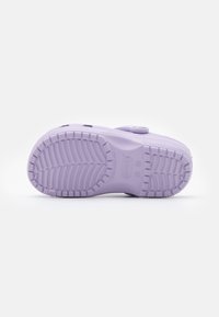 Sole di scarpa in gomma viola con presa testurizzata, dettaglio a logo circolare e un bordo leggermente rialzato attorno al plantare.