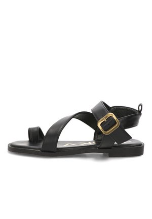 Sandalia plana de cuero negro con tiras cruzadas, lazo para el dedo y una gran hebilla dorada en la correa del tobillo.