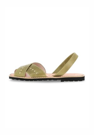Green suede sandal with crisscross straps, circular metal studs, and a back strap. Flat black sole with textured bottom.