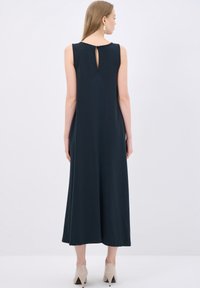 Vestito senza maniche di un intenso blu navy con una silhouette fluida, caratterizzato da un dettaglio a forma di chiave sul retro. Tessuto morbido, lunghezza alla caviglia e vestibilità ampia.