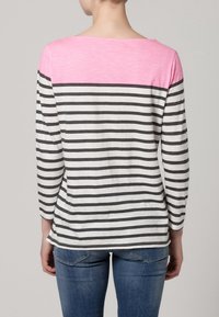 Lightweight, long-sleeve shirt featuring a pink upper portion and gray and white horizontal stripes below, with a relaxed fit and soft texture.