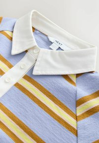 Polo a maglia a righe con colletto e pattina bianchi, dotato di bottoni e righe diagonali in senape, giallo e rosa su uno sfondo azzurro chiaro.