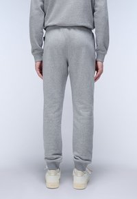 Grijze katoenen joggingsbroeken met een ontspannen pasvorm en taps toelopende boorden, gecombineerd met witte lage sneakers. Eenvoudige, gladde textuur zonder patronen.