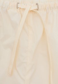 Jasnobeżowe szorty na sznurku wykonane z gładkiego, lekkiego materiału. Posiadają elastyczny pasek w talii oraz dekoracyjną kokardę z przodu.