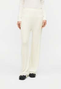 Παντελόνια πλεκτά σε κρεμ απόχρωση με φαρδιά γραμμή, διαθέτουν ελαστική μέση και υφή. Συνδυασμένα με μαύρα φλατ παπούτσια.