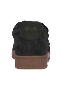 Mustat nahkakengät, joissa on ruskea kumipohja. Varustettu pehmustetulla kauluksella, jossa on Clarks-logot takana, ja tekstuurinen pinta.