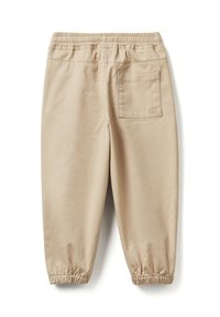 Beżowe spodnie z elastycznym pasem, z pojedynczą kieszenią z tyłu po prawej stronie oraz elastycznymi mankietami przy kostkach.