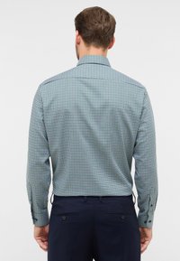 Geruite langetermijnshirt met een groen, marineblauw en wit patroon. Heeft een klassieke kraag, knoopmanchetten en een licht getailleerde pasvorm.