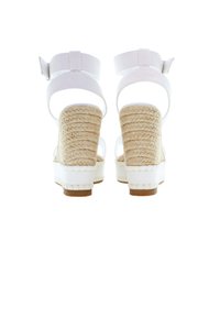 Sandalias de cuña blancas con tacones de yute trenzado, correas en el tobillo ajustables y una suela texturizada. Diseño limpio con materiales suaves.