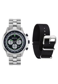 Montre chronographe Breil avec bracelet en métal argenté et cadran noir, accompagnée d'un bracelet en tissu noir séparé avec boucle en argent.