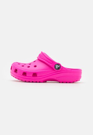 Clog in gomma rosa con un design perforato, una fascia sopra, suola testurizzata e un accento a logo circolare sul lato.