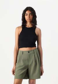 Black cropped tank top with ribbed texture paired with high-waisted, pleated olive green shorts featuring a button closure and side pockets.