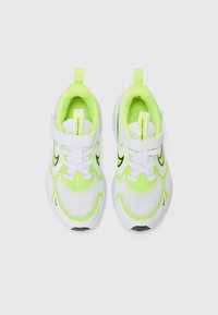 Baskets blanches de sport avec des accents vert fluo, tige en maille, système de laçage et une languette en boucle au talon pour un enfilage facile. Détails du logo noir présents.