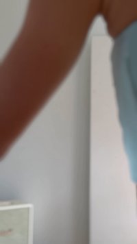 Μερικώς ορατό άτομο που φοράει ανοιχτό μπλε ρούχα σε ουδέτερο εσωτερικό χώρο με ντουλάπι στο φόντο.