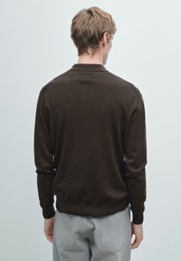 Maglione marrone scuro lavorato a maglia con maniche lunghe e collo a polo. Presenta polsini e orlo a coste, progettato per una silhouette aderente.