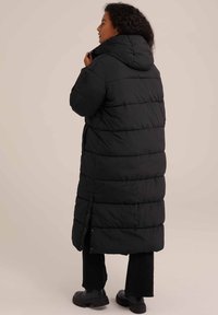 Melna gara puffer mētne ar kapuci, ar quilted dizainu, pogu aizdari sānos un brīvu piegriezumu.