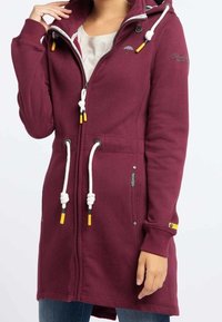 Sudadera larga de color granate hecha de mezcla de algodón, con cremallera, cordones ajustables y bolsillos delanteros. Con detalles en amarillo.