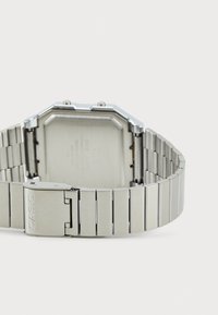 Montre en acier inoxydable avec un boîtier octogonal, finition métal brossé, et un fermoir portant le nom de la marque "CASIO" sur le bracelet.