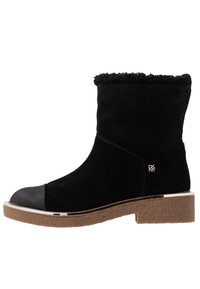 Svart mocka känga som når till mitten av vadet, med shearling-fodring, gummitåhätta, liten silverlogotyp och strukturerad brun sula med låg klack.