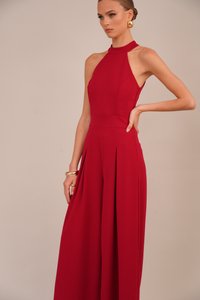 Punainen halterneck-mekko, jossa on pleated-latvasaumat ja leveät lahkeet, valmistettu sileästä kankaasta. Ominaisuudet istuva yläosa ja avonainen selkädesign. Näkyvänä kultaketjua.
