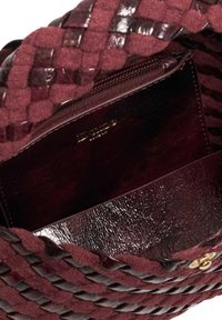 Burlywood handbag with woven textured exterior in deep burgundy, featuring a smooth leather interior and zippered pocket. Gold hardware detail.