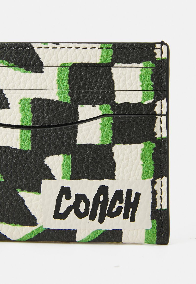 Tarjetero de cuero en blanco y negro con acentos verdes; presenta una superficie texturizada, múltiples ranuras para tarjetas y un logo impreso.