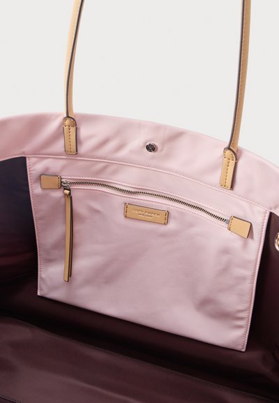 Εσωτερικό ροζ και καφέ τσάντας tote που δείχνει τσεπάκι με φερμουάρ και μπεζ ταινία τραβήγματος, καθώς και μπεζ δερμάτινες λαβές.