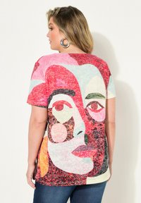 Camiseta multicolor con un diseño de cara abstracta que presenta formas audaces y texturas variadas. Fabricada con una tela ligera.
