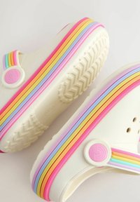 Valged kummist klotskingad erksate vikerkaare triipudega roosas, kollases ja lavendlis. Neil on ümmargune logo ja reljeefse mustriga tallaosa.
