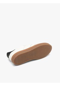 Sneaker con punta e tallone in pelle nera, tomaia in tessuto bianco con strisce diagonali e suola in gomma marrone con grip testurizzato.