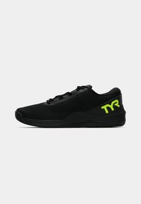 Zapatillas deportivas negras con un upper de malla texturizada, suela plana y el logo verde "TYR" en el lateral. Presenta un diseño tradicional de cordones.