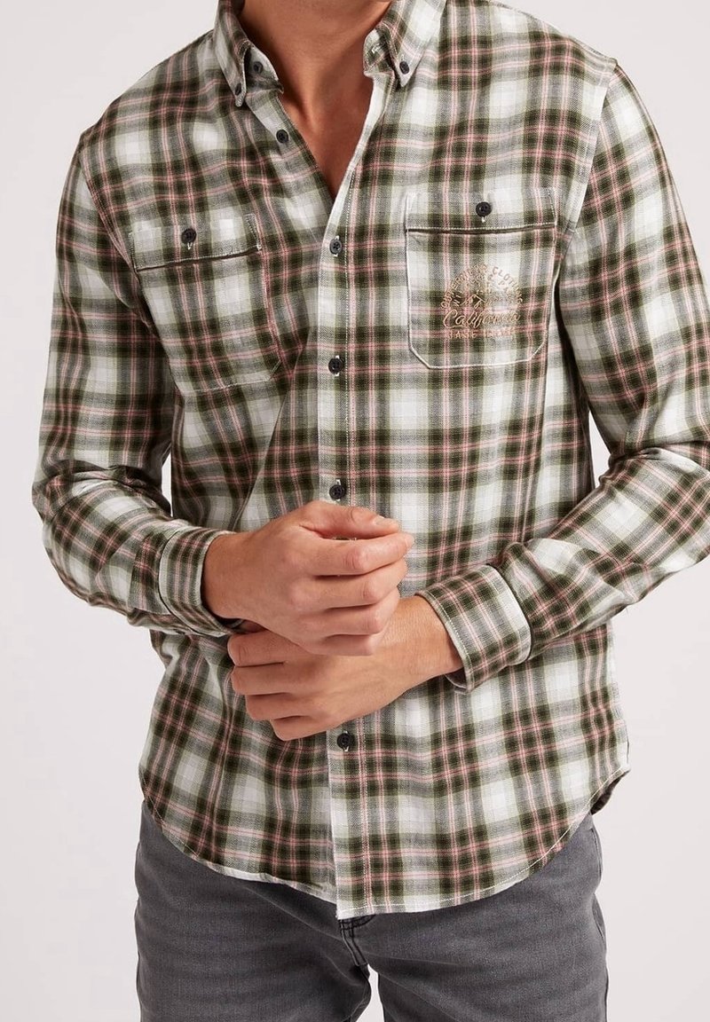 Groen en wit geruite overhemd met roze accenten, met knoopsluiting kraag, twee borstzakken en geborduurde details op de zak. Lange mouwen.