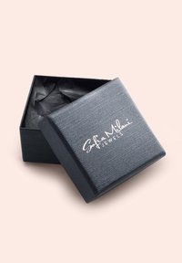 Scatola per gioielli nera e testurizzata con un logo argentato, leggermente aperta per rivelare della carta velina nera spiegazzata all'interno.