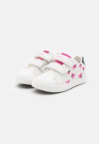 Zapatillas blancas para niños con un patrón de lunares rosas, tiras de velcro, punta redondeada y detalles grises en el talón. Marca Geox en las tiras.