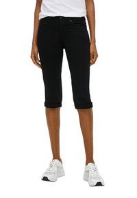 Pantalons capri en denim noir avec des poignets roulés. Design à cinq poches, passants de ceinture et taille standard. Assortis à des chaussures de sport blanches.