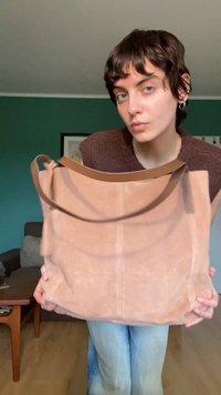 Grand sac fourre-tout beige doux avec une texture lisse, une forme allongée et des détails de couture minimalistes. Dispose d'une simple sangle large pour l'épaule.