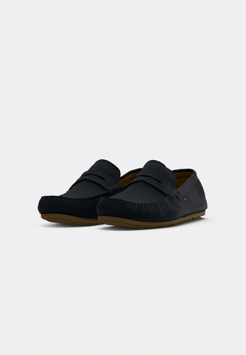 Czarne zamszowe loafersy z przeszytymi detalami, płaskimi gumowymi podeszwami i gładką fakturą. Projekt charakteryzuje się lekkim obcasem i minimalnymi akcentami.