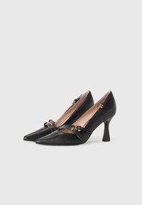 Escarpins noirs en cuir avec des bouts pointus, un petit matériel d'accent en or et un design de talon courbé unique. Texture lisse et silhouette épurée.