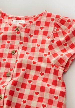 Red and cream checkered short-sleeve shirt with small heart patterns, featuring wooden buttons and a round neckline. Cotton material.
