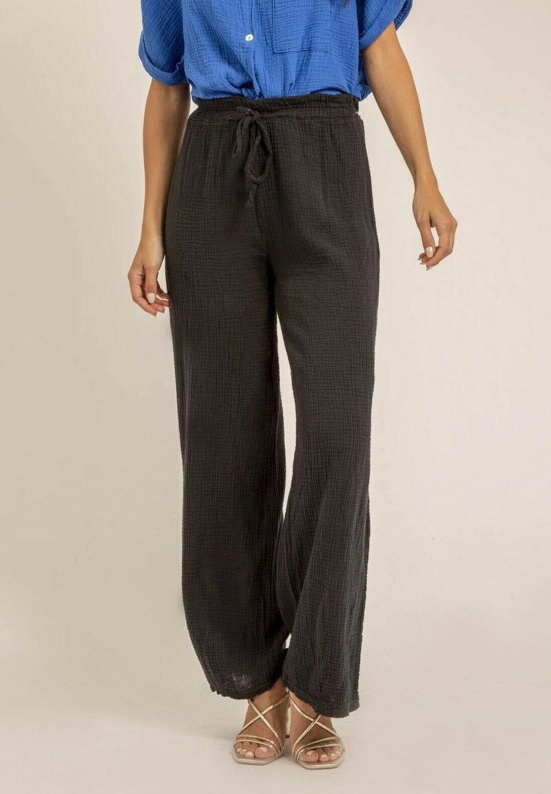 Pantalons légers, noirs, à jambes larges avec un tissu texturé, dotés d'une taille élastique et d'un cordon de serrage. Associés à une chemise bleue.