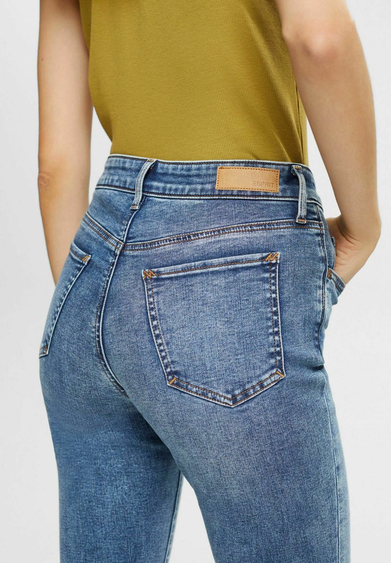 Blaue Jeans aus Denim mit hoher Taille, zwei Gesäßtaschen, dezenten Nähten und einem hellbraunen Leder-Logopatch am Bund.