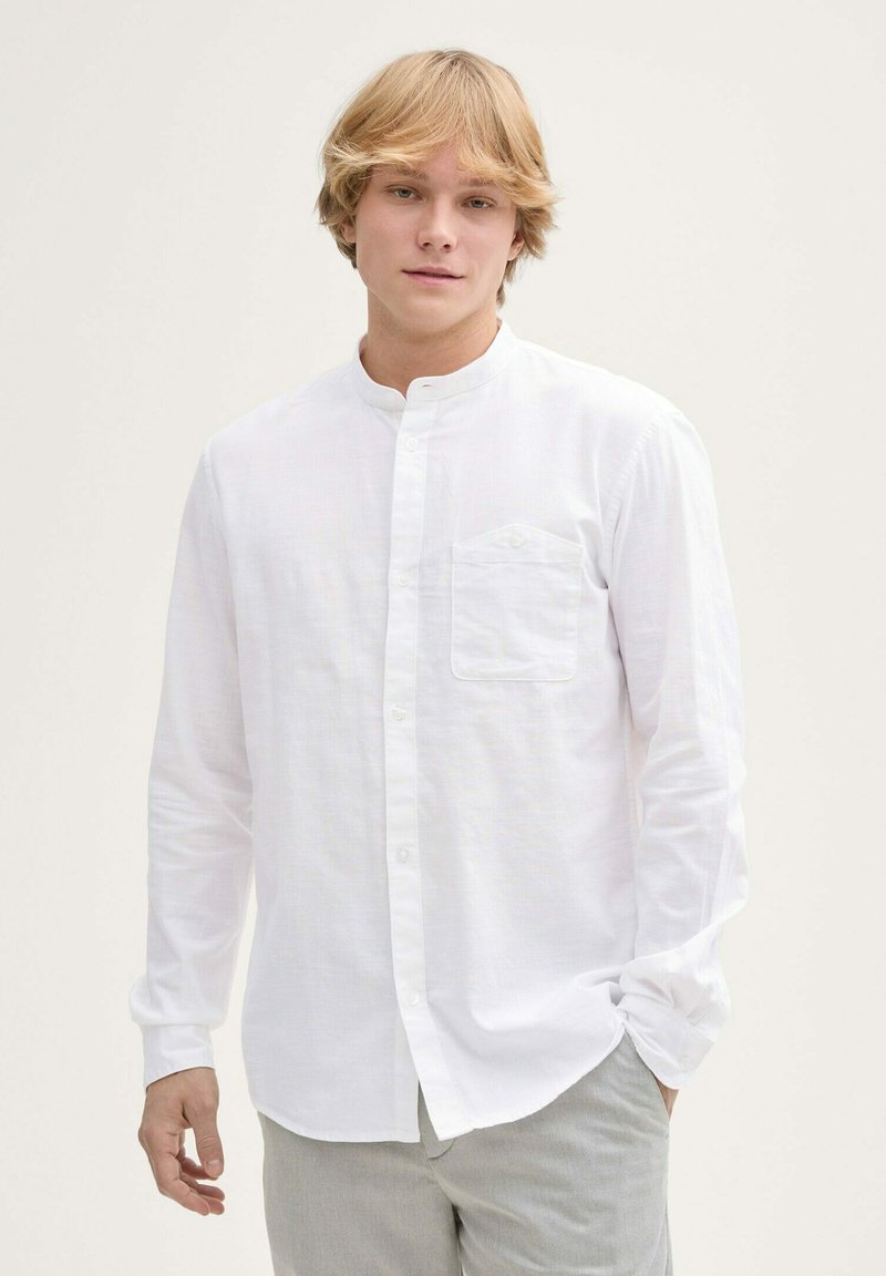 Weißes Langarmhemd mit Stehkragen, ausgestattet mit einer kleinen Brusttasche und einer Knopfleiste, aus leichtem Stoff gefertigt.