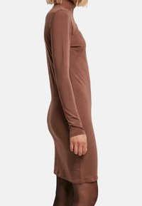 Abito a collo alto marrone, design aderente, maniche lunghe, texture liscia, lunghezza al ginocchio, con tessuto leggermente elasticizzato per il comfort.