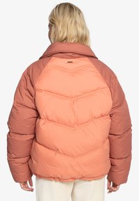 Pufferjakke i koral- og ferskenfarver med et chevronmønster, stor krave og vandret syninger; blød tekstur, isoleret design.