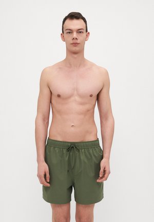 Grüne Badehose aus leichtem Material mit einem elastischen Bund und einer Kordel. Das Design zeigt eine einfache, einfarbige Ausführung.