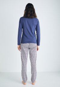 Långärmad marinblå topp som matchas med mönstrade pyjamasbyxor med ett zigzag-mönster i marinblått och vitt. Mjuk, lätt tyg med en avslappnad passform.