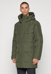 Olívaszínű bélelt parka kapucnival, több első zsebbel, cipzáras bezárással és laza szabással. Sima, matt felületű anyag.
